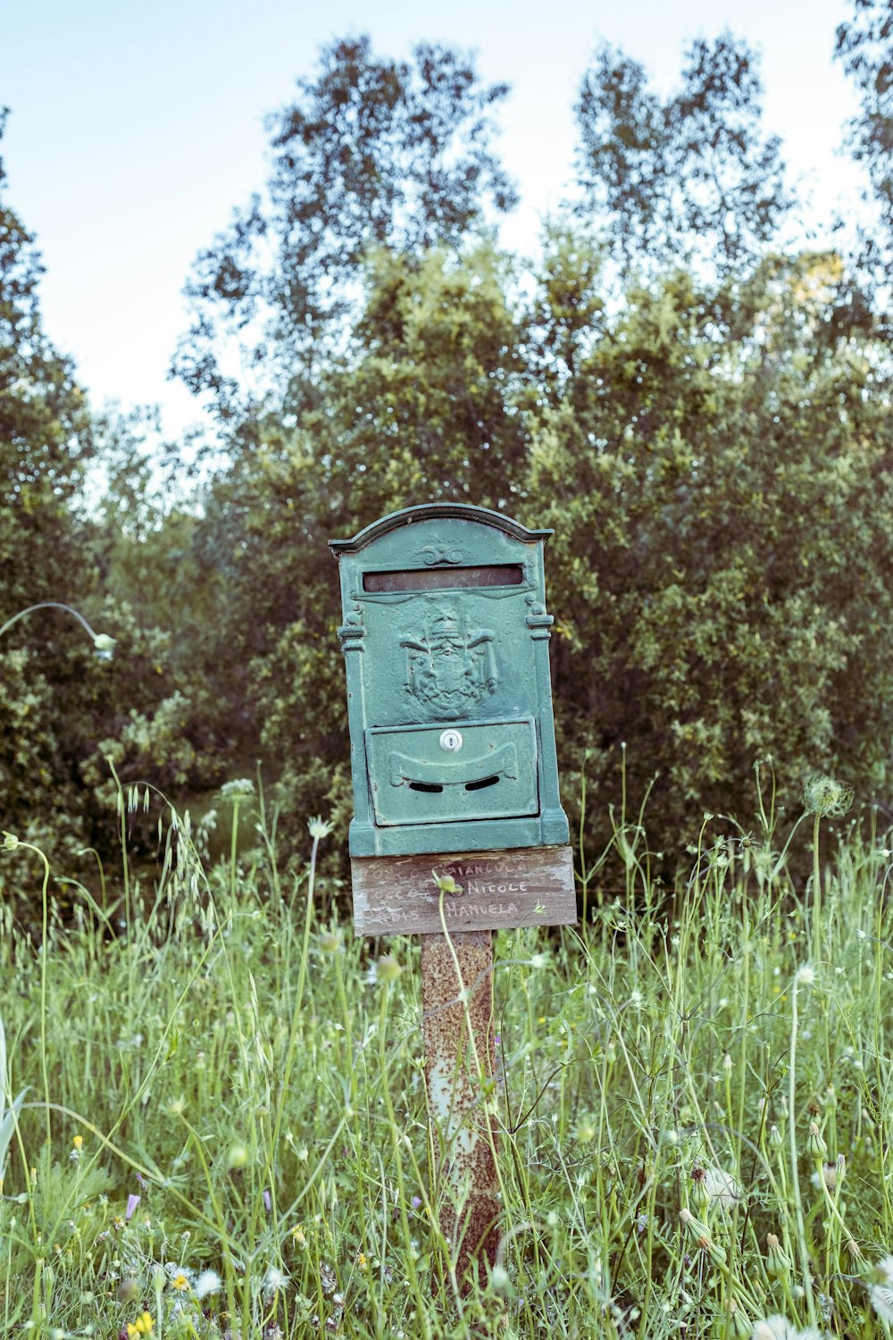 green mailbox on wooden post on grass