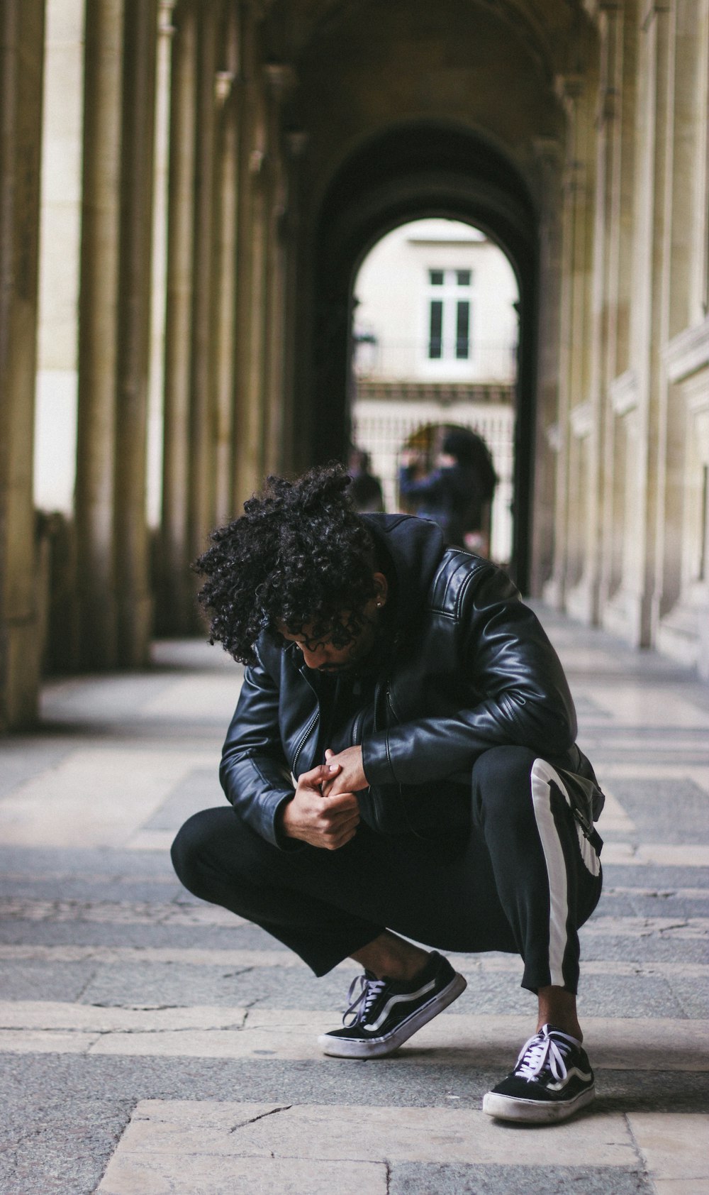 man in black leather jacket under concrete building