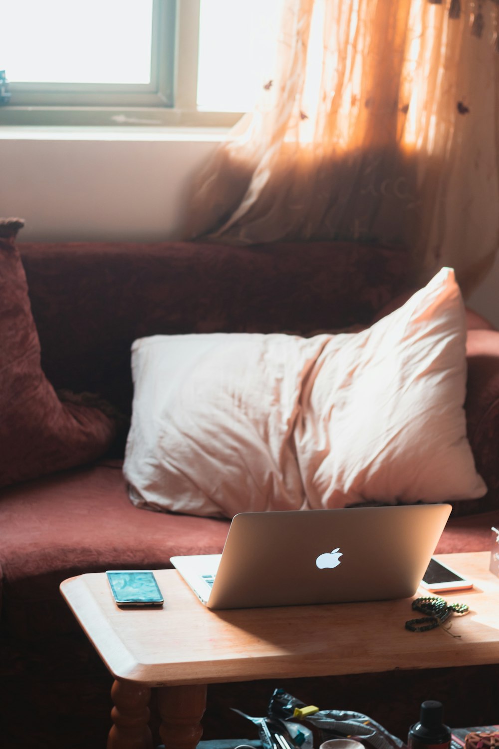 white pillow on red couch and MacBook Air near iPhone on wooden coffee table