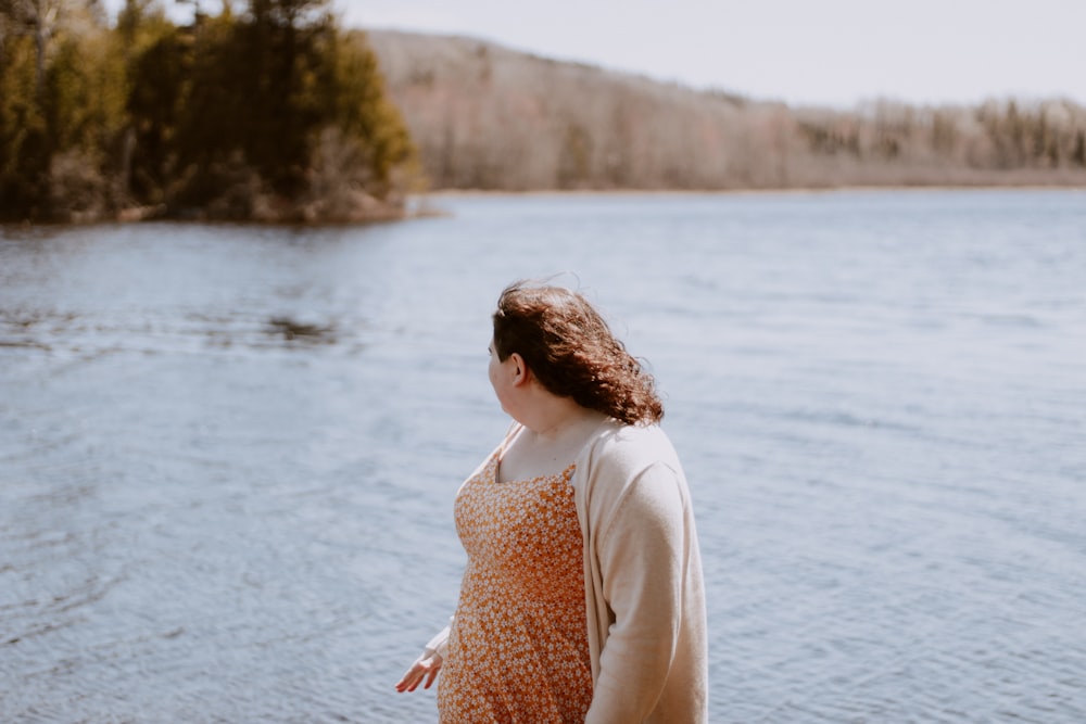 mulher vestindo cardigan cinza olhando para o corpo de água