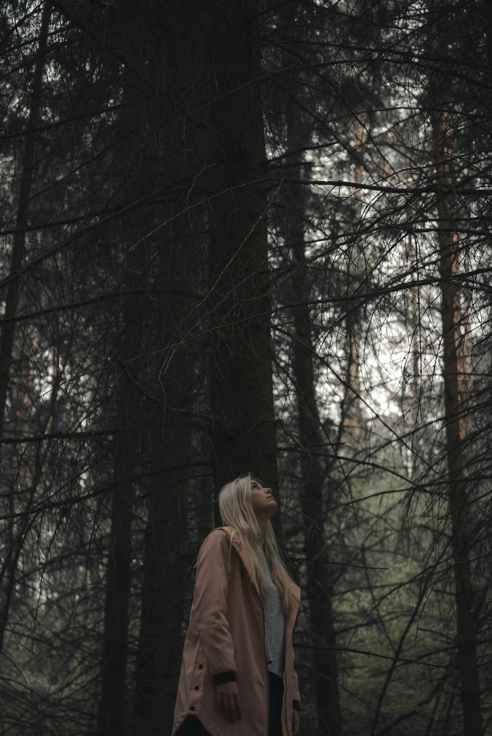 woman in coat standing near trees