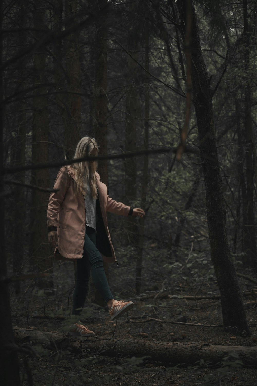 woman in gray coat walking under trees