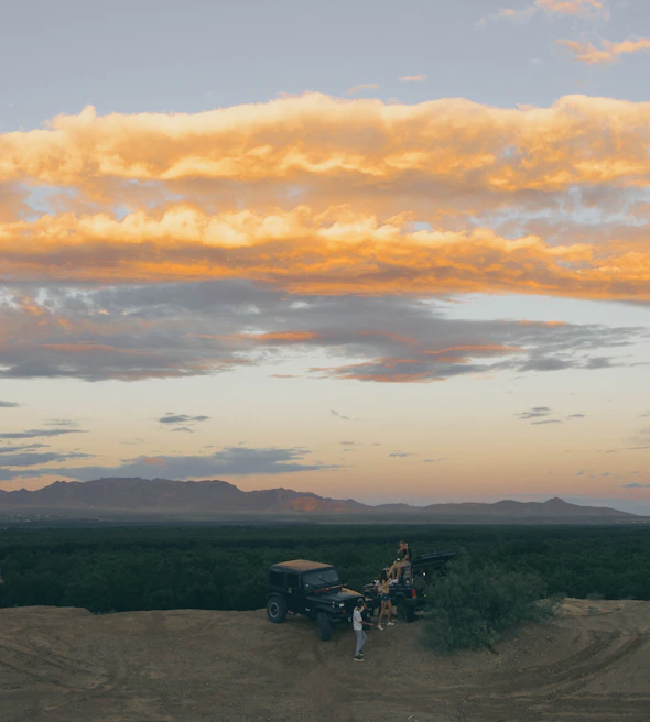 Travelers enjoying a scenic view from a hilltop near Calicut, with Supersafri vans in the background.