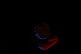 Close-up of hands performing energy healing techniques with deep red and white tones.