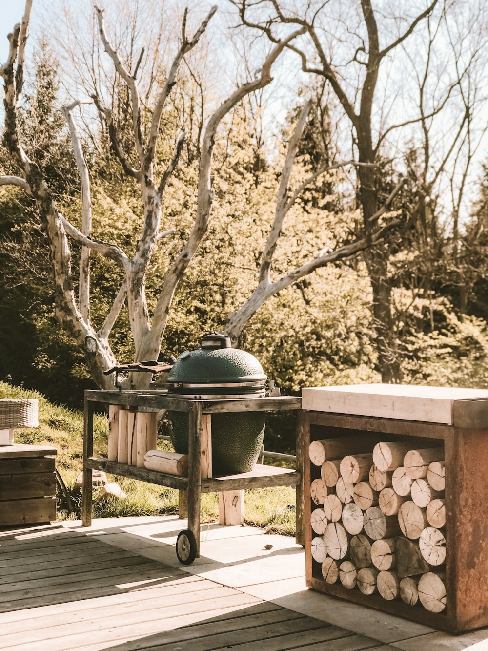 green kamado near pile of firewoods