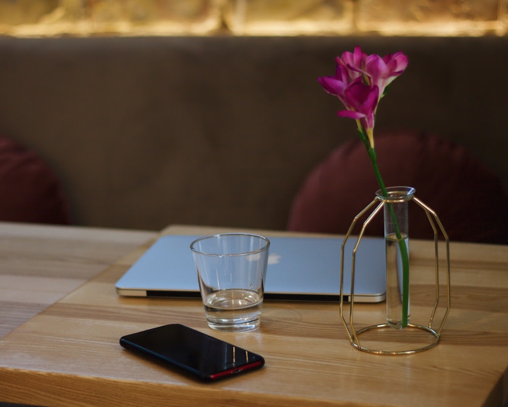 clear shot glass beside black smartphone