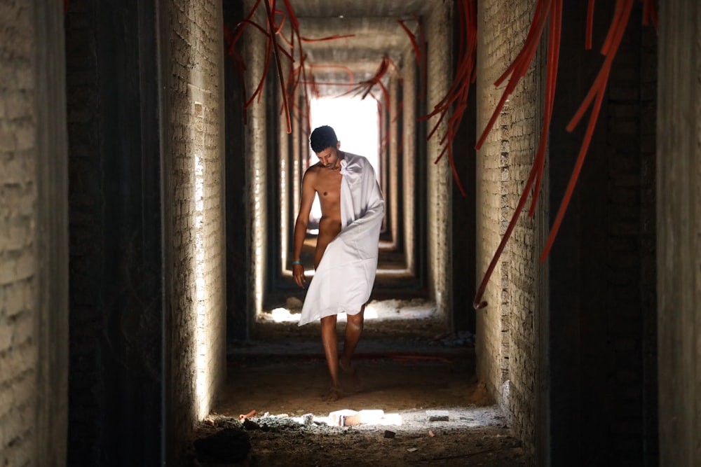 man with white towel walking on hallway