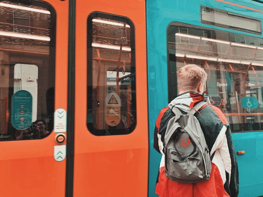 person standing near white and orange train