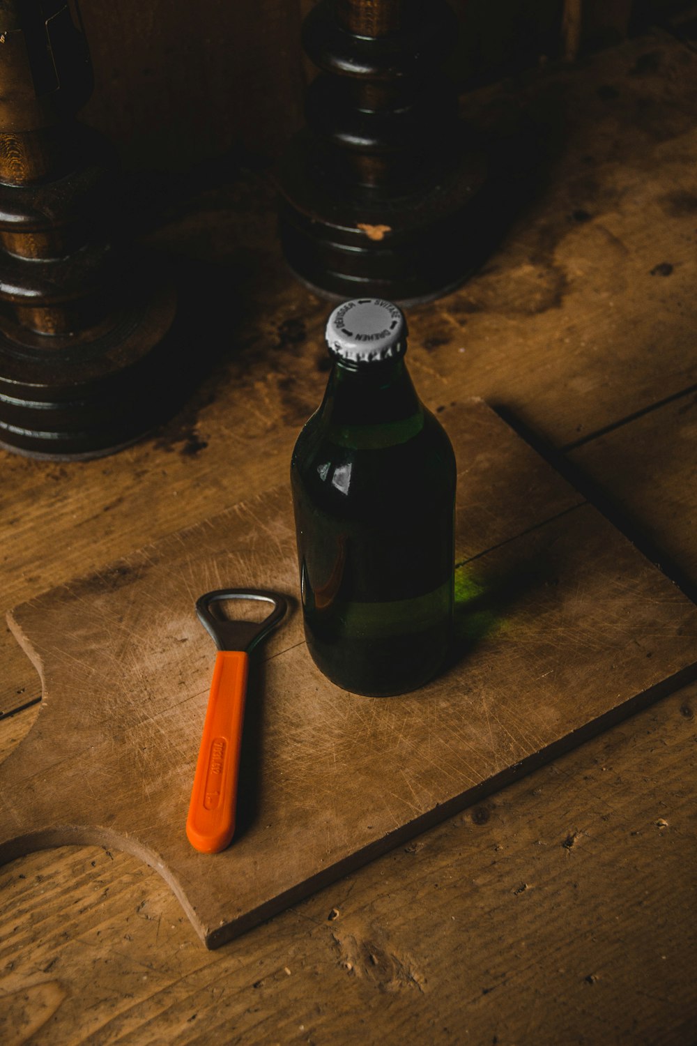 liquor bottle beside bottle opener on brown wooden chopping board
