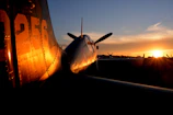 An advanced airplane prototype taxiing on a runway at sunset.