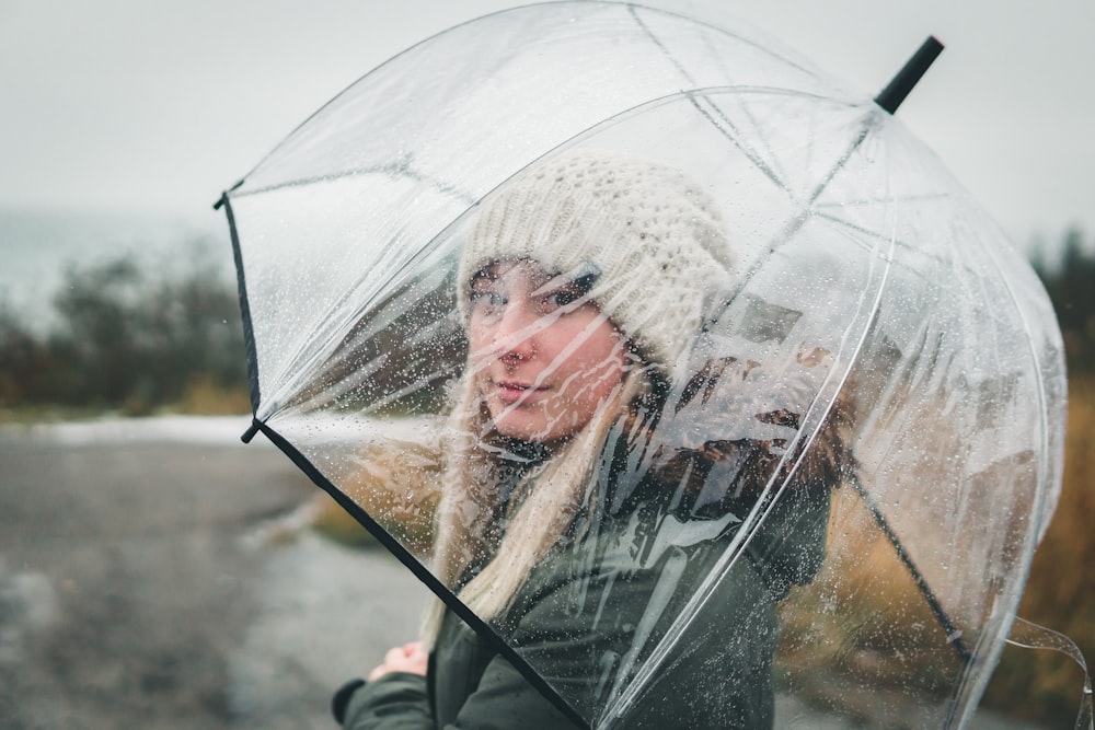 woman in white bonnet holding clear umbrella