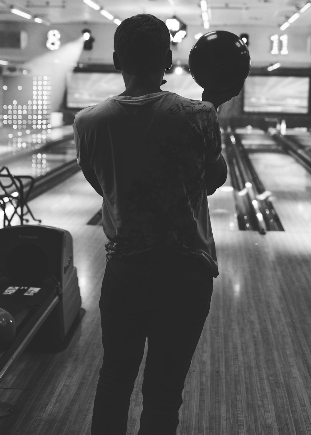grayscale photo of man holding bowling ball