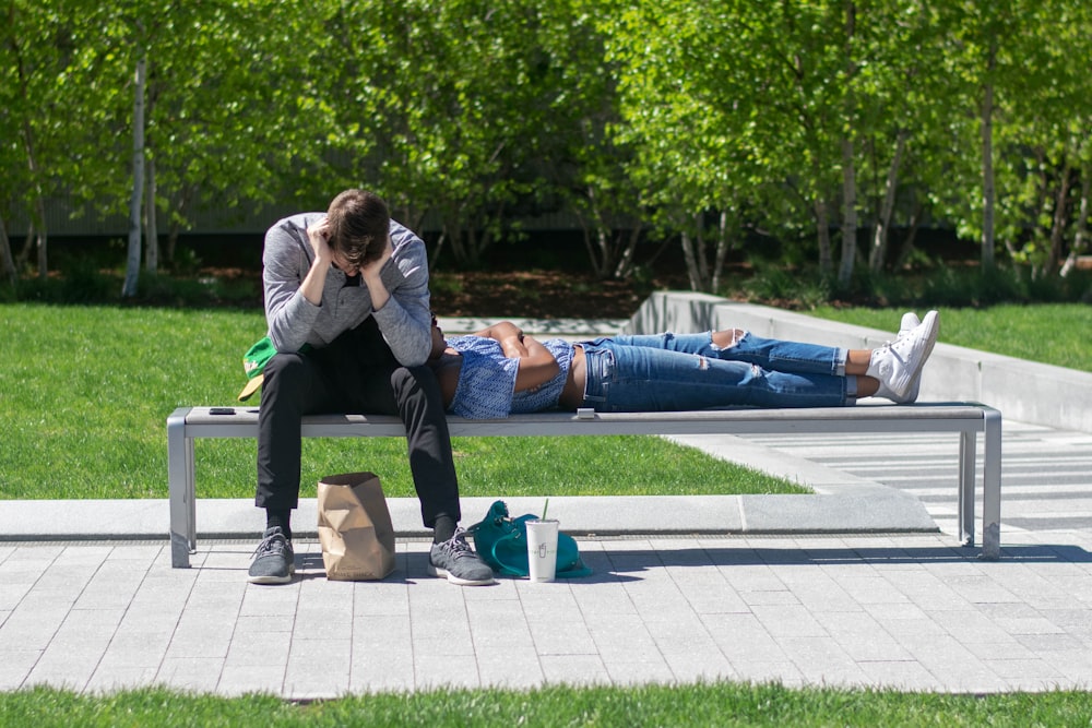 man sitting on white metal bench during daytime