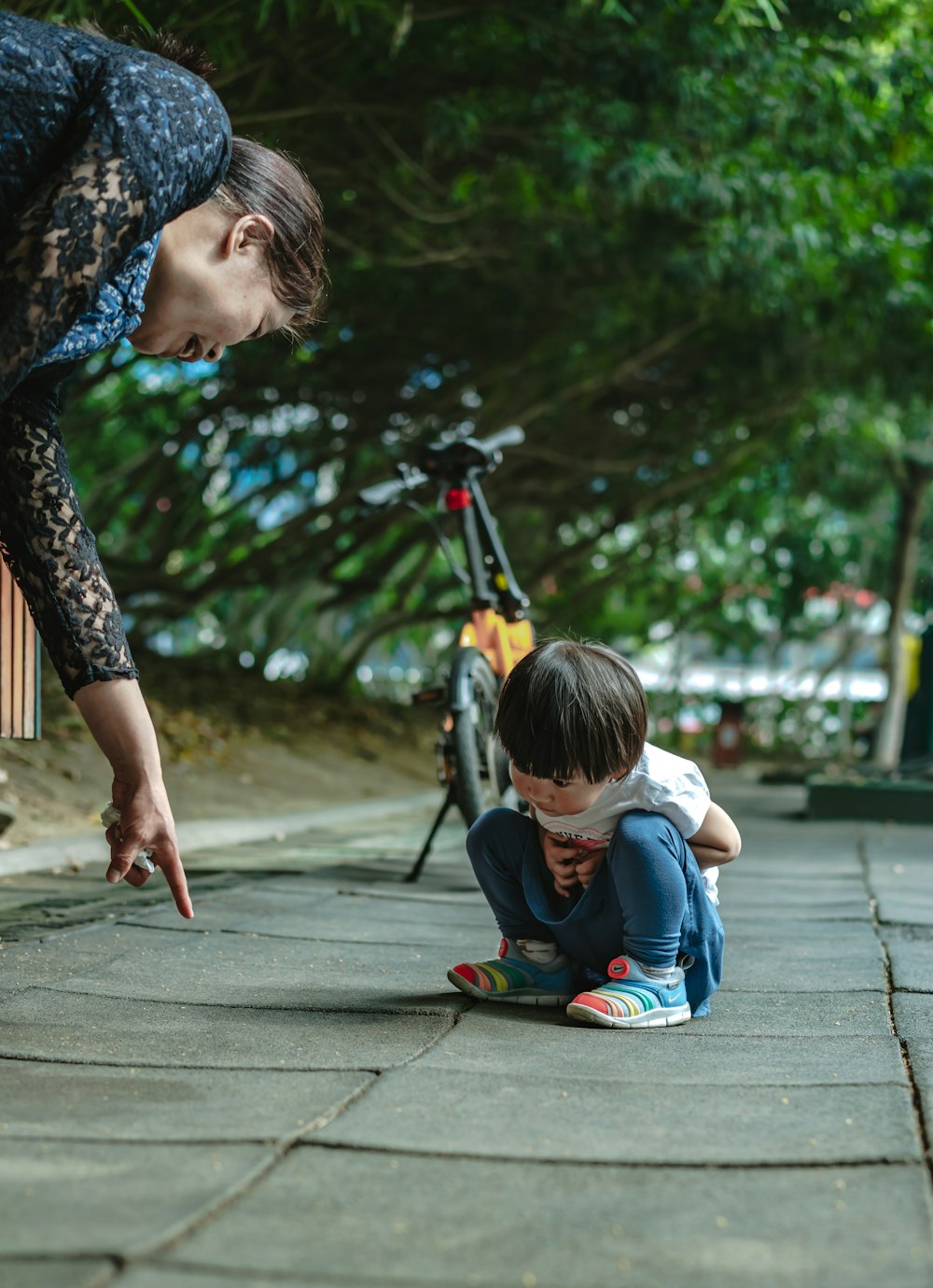 woman pointing on the ground while child watching