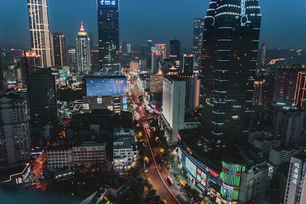 A bustling cityscape at night illuminated by colorful lights and skyscrapers