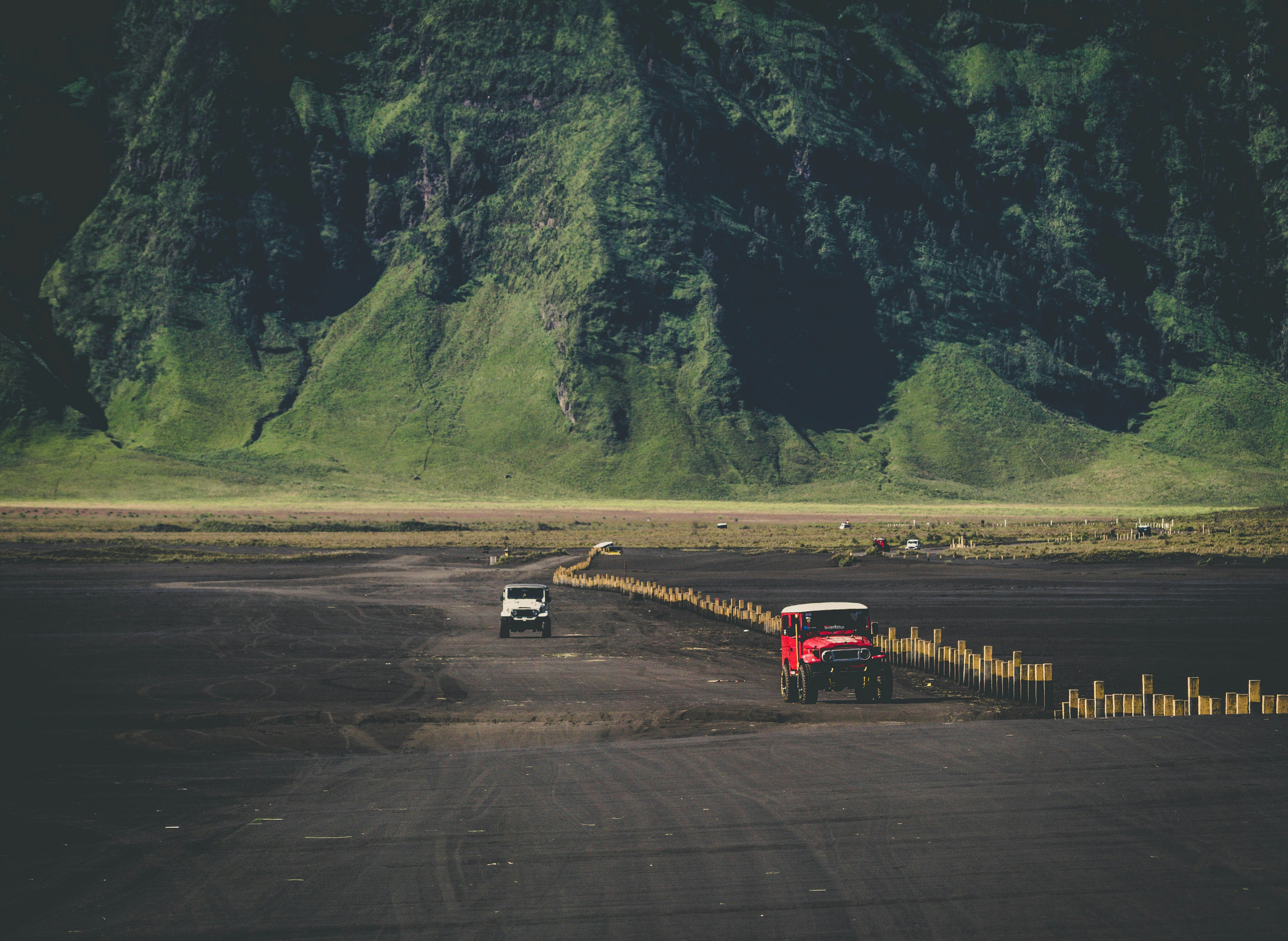 SUVs on dirt road in front of mountain