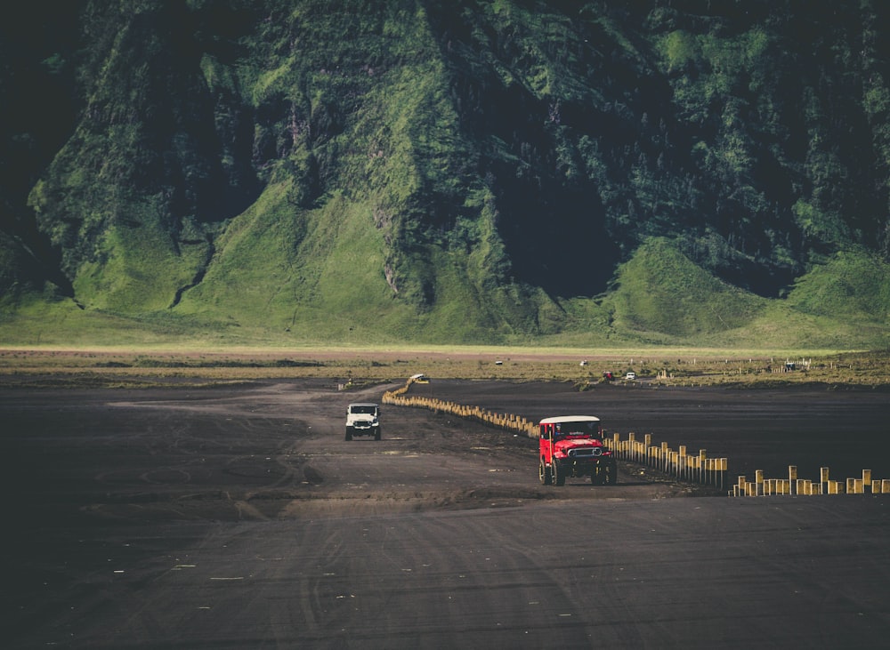 SUVs on dirt road in front of mountain