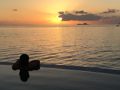 Traveler capturing the sunset from a cliffside infinity pool with panoramic views.