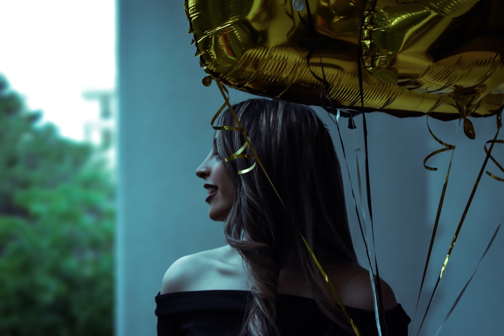 woman in black off-shoulder top holding gold balloon