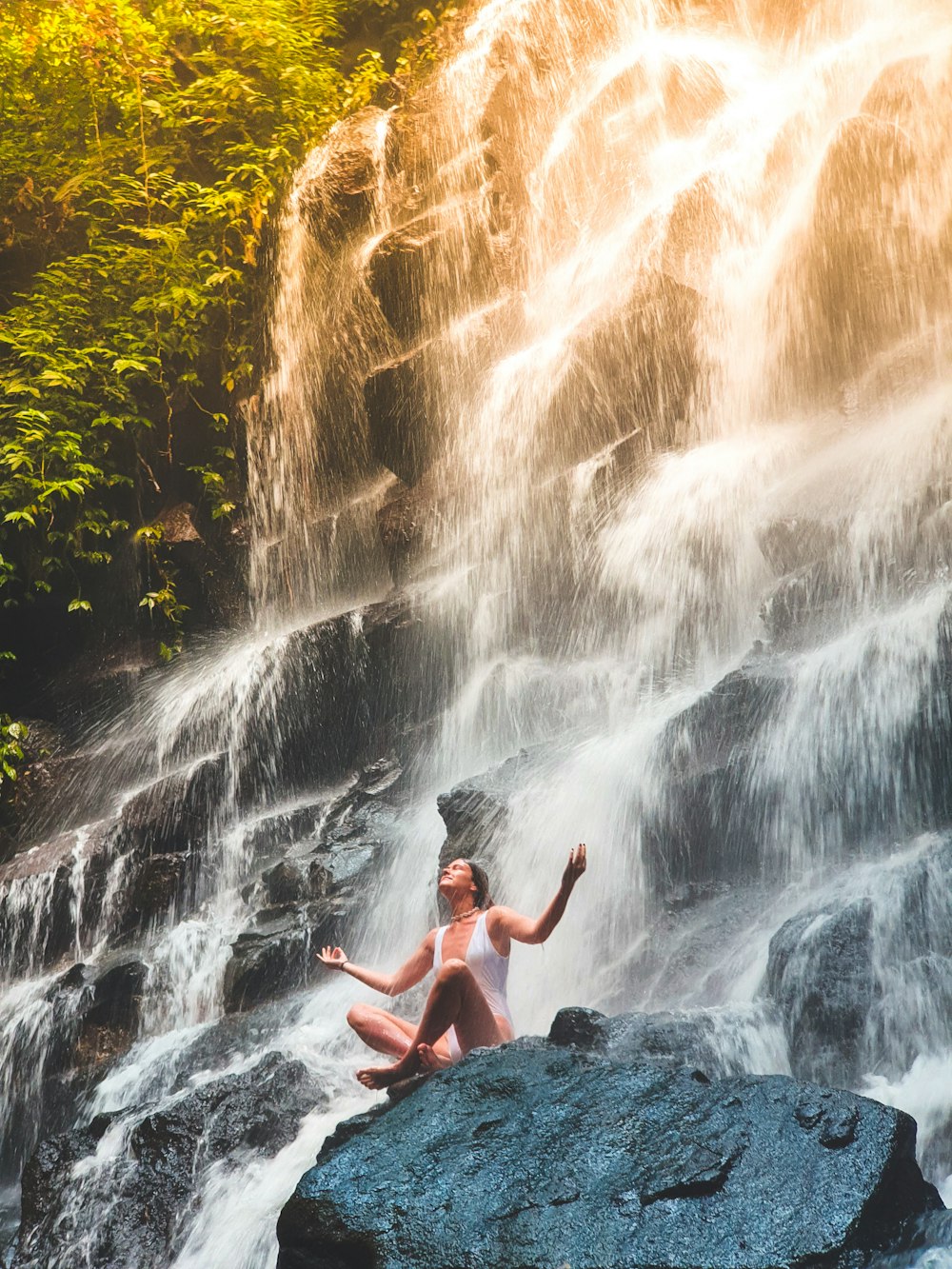 Mujer en monokini blanco sentada en la roca