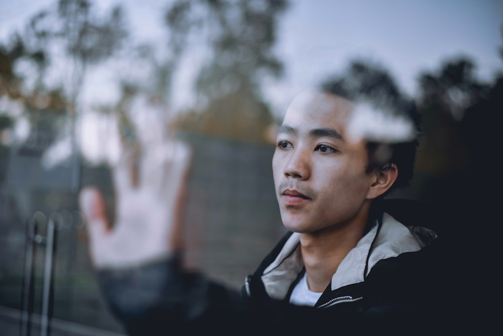 man putting his left hand on clear glass window