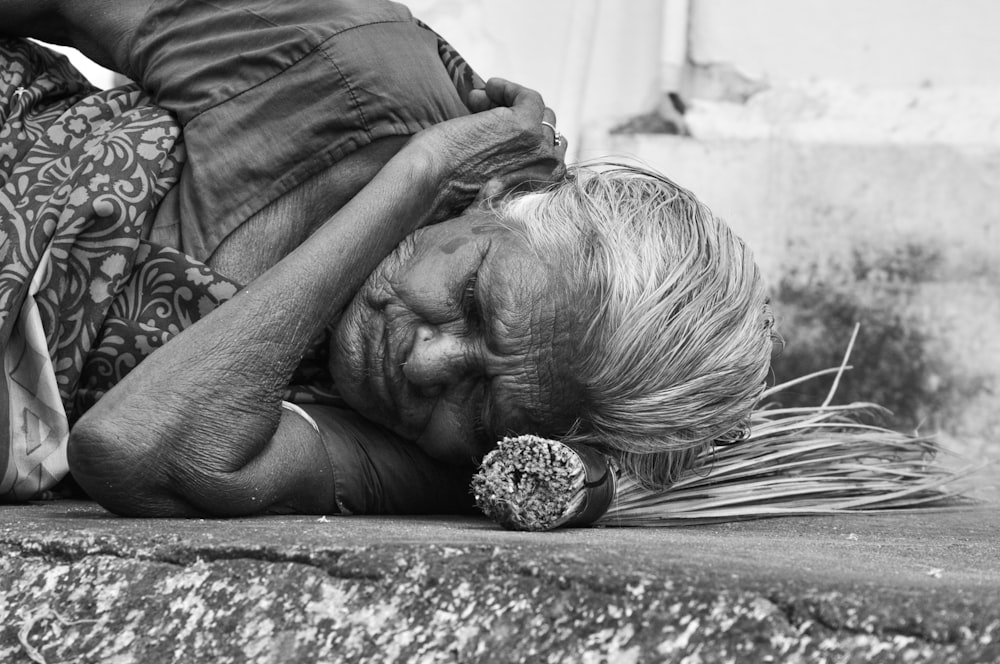 women sleeping on a concrete surface grey-scale photography