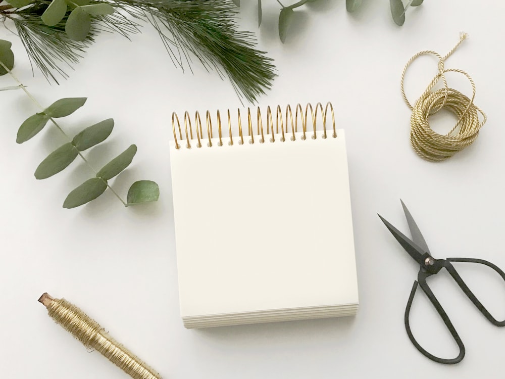 white spiral notepad between pen and scissors