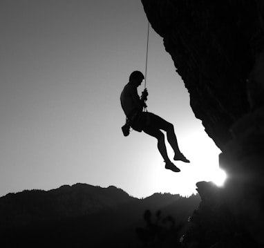 man hanging on cliff