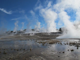 A geothermal plant nestled in a rugged landscape with steam rising from vents.