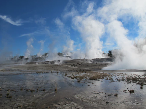 A geothermal plant nestled in a rugged landscape with steam rising from vents.