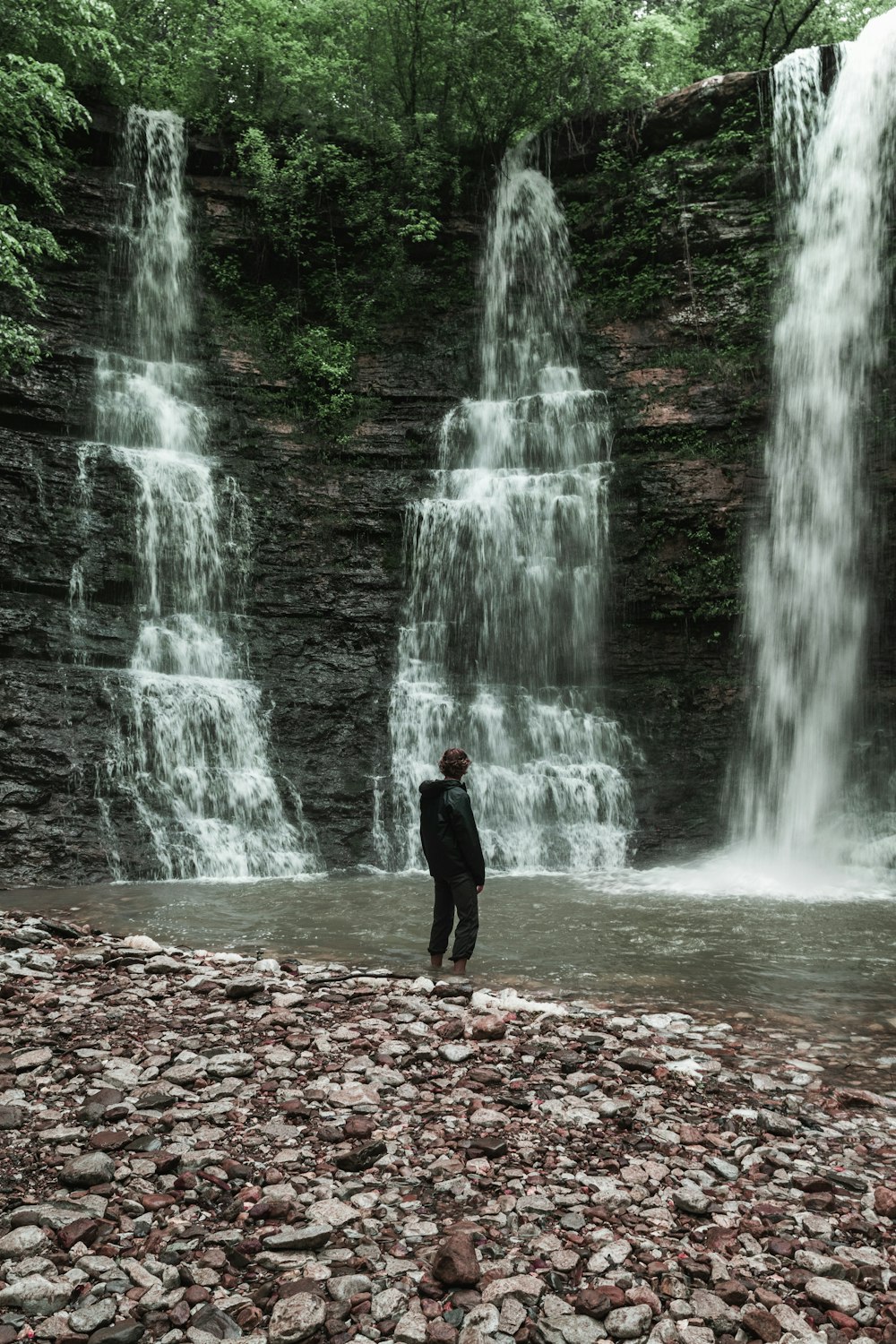 man standing near waterfalls