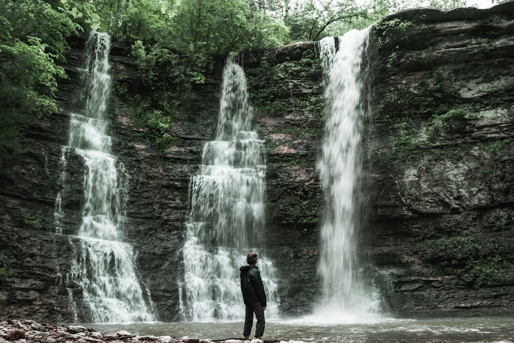 man standing near waterfalls