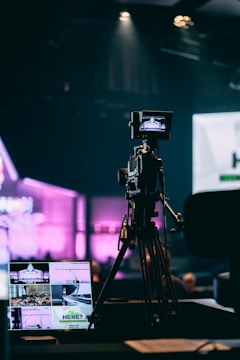 selective photo of camera with tripod and laptop computer turned on