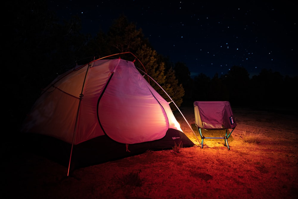 light coming from pink and orange tent near pink camping chair