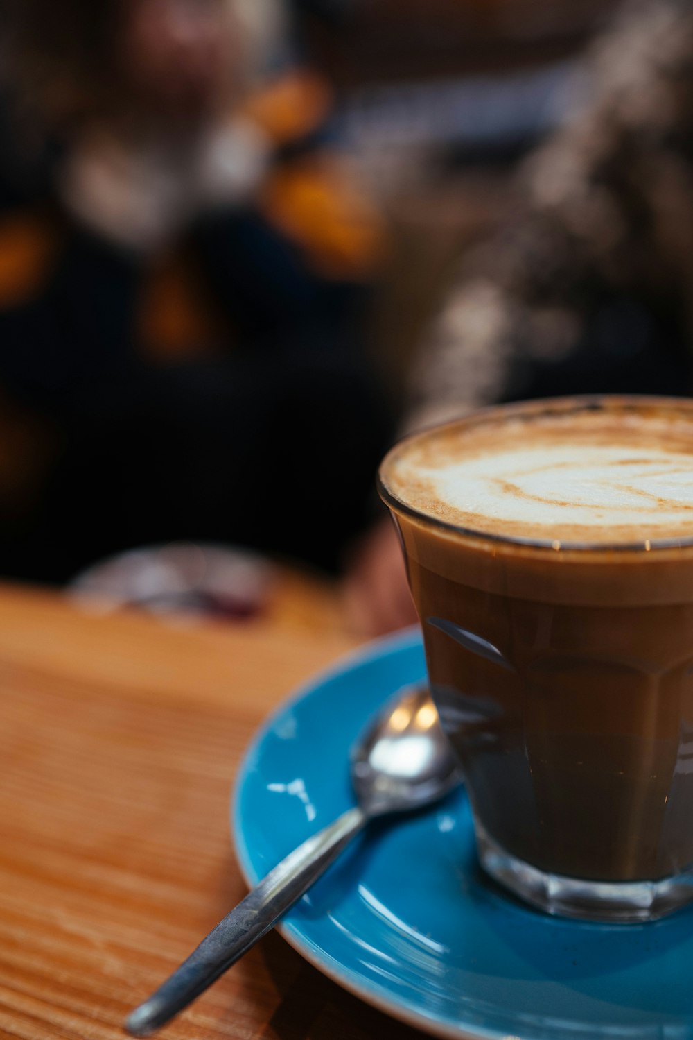 cappuccino on clear glass near gray stainless steel teaspoon