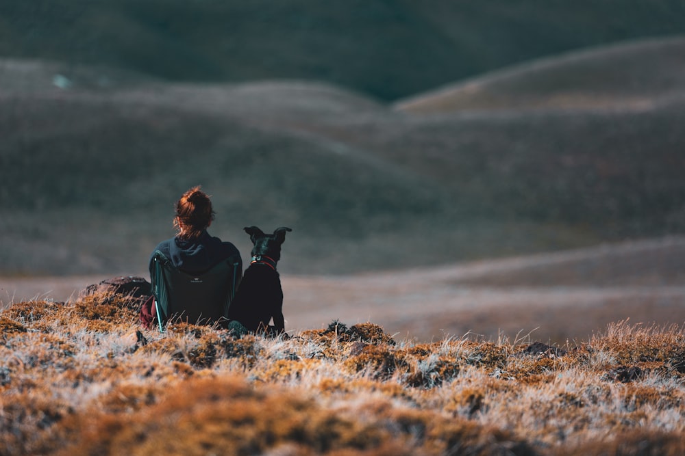 woman sitting beside black dog