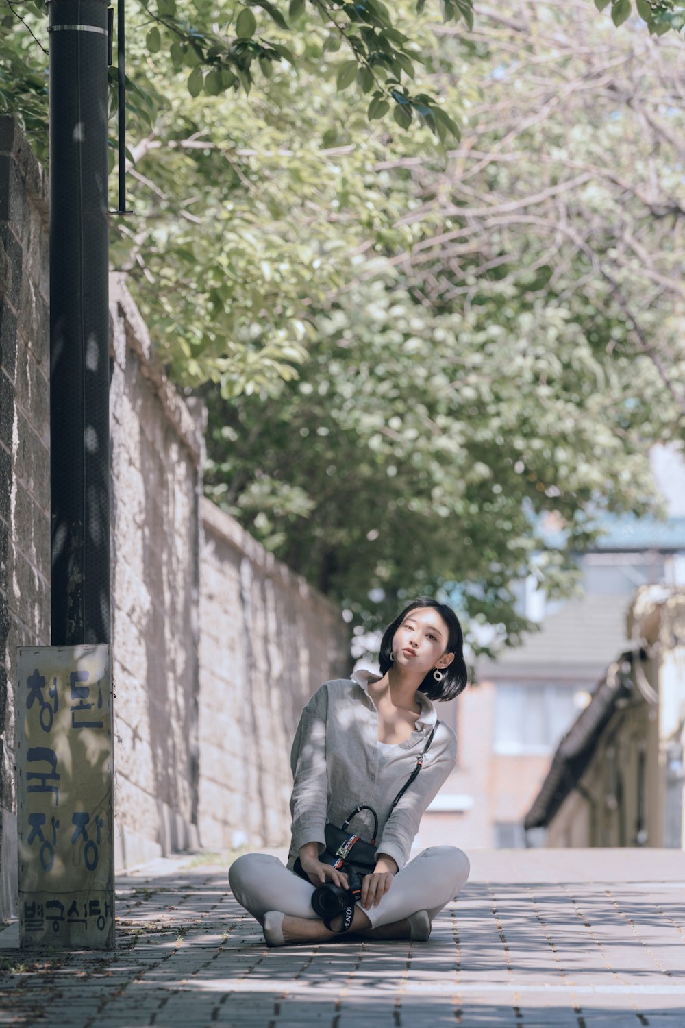 woman wearing grey long-sleeved shirt sitting on street