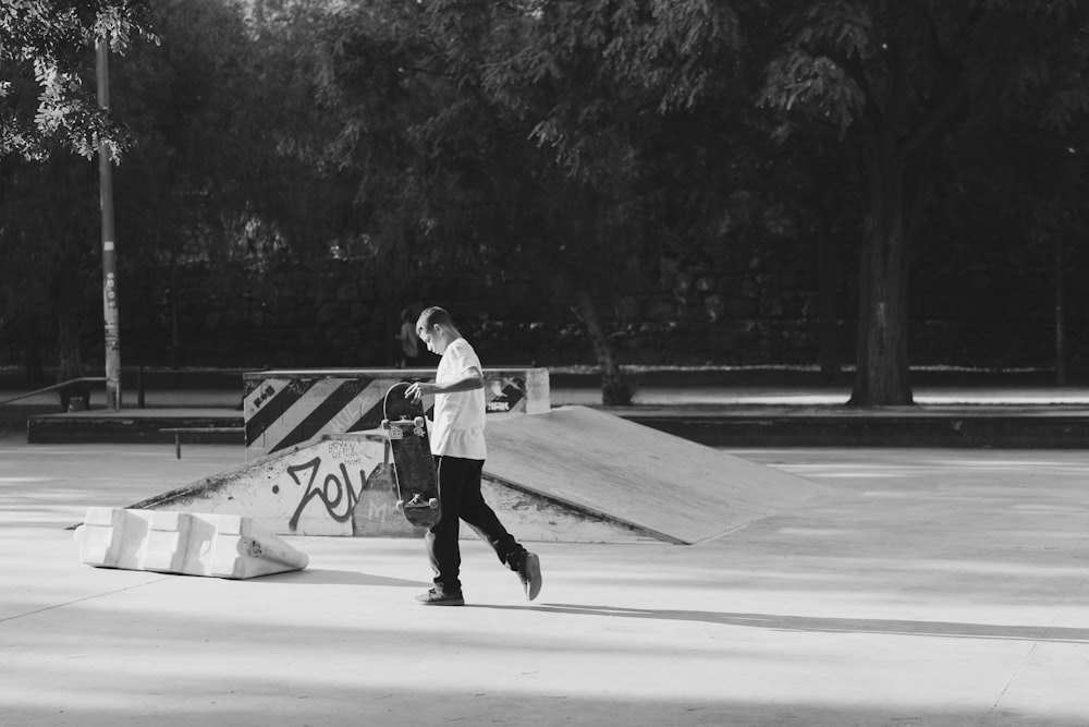 homme tenant une planche à roulettes marchant près de la rampe