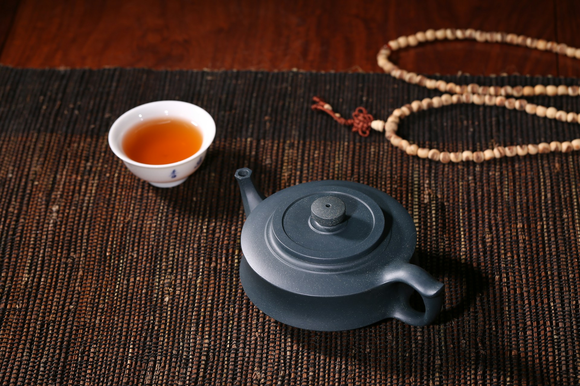 white ceramic teacup beside black ceramic teapot