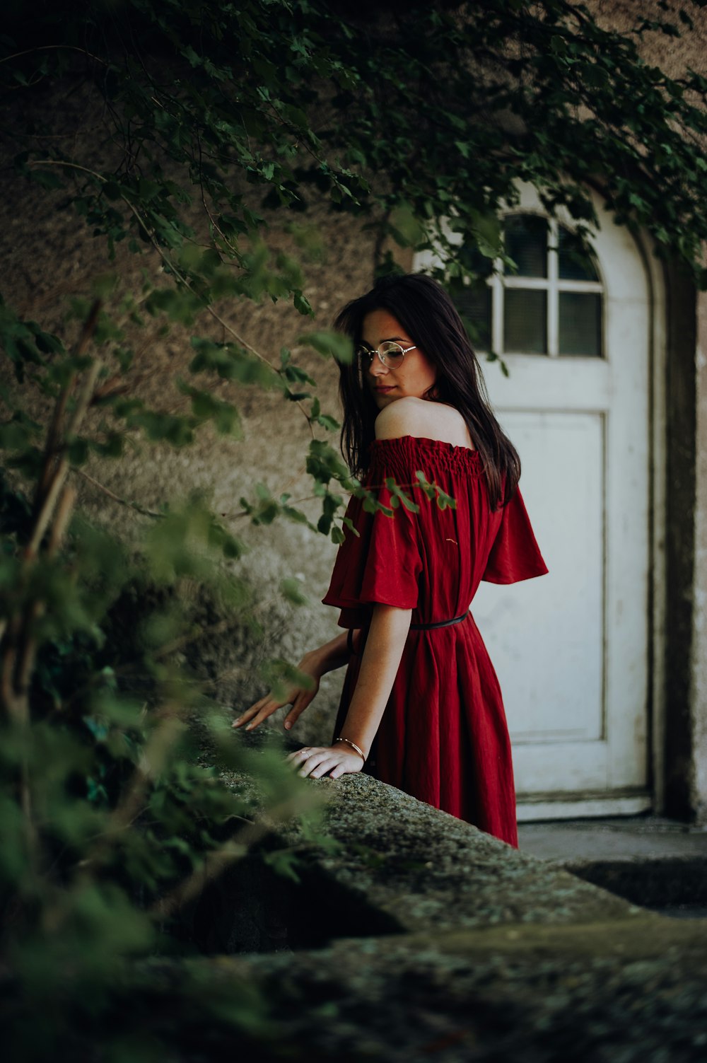 woman in red off-shoulder short-sleeved dress near brown concrete building