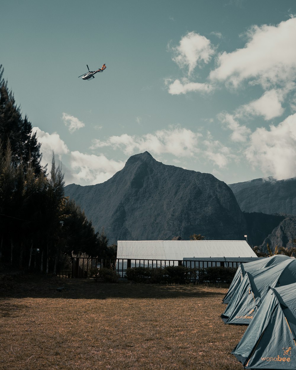 helicopter in mid air above house and mountain