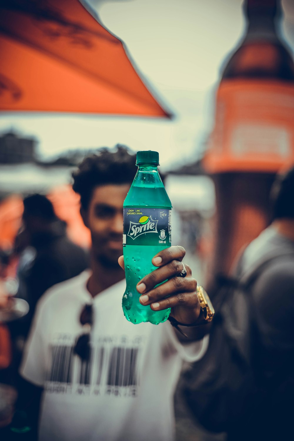 hombre con camisa blanca sosteniendo una botella de Sprite