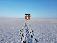 A snow-covered cottage with footprints leading to the front door during winter monitoring.
