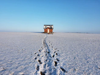 A snow-covered cottage with footprints leading to the front door during winter monitoring.