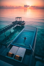 woman swimming in infinity pool at sunrise