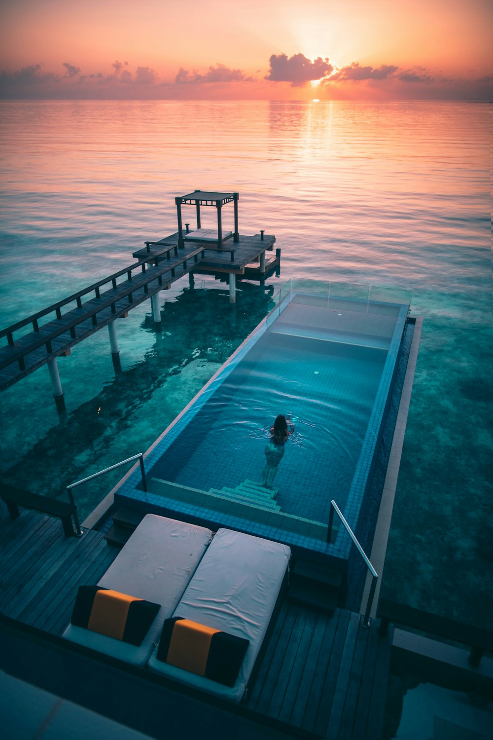 Mujer nadando en piscina infinita al amanecer