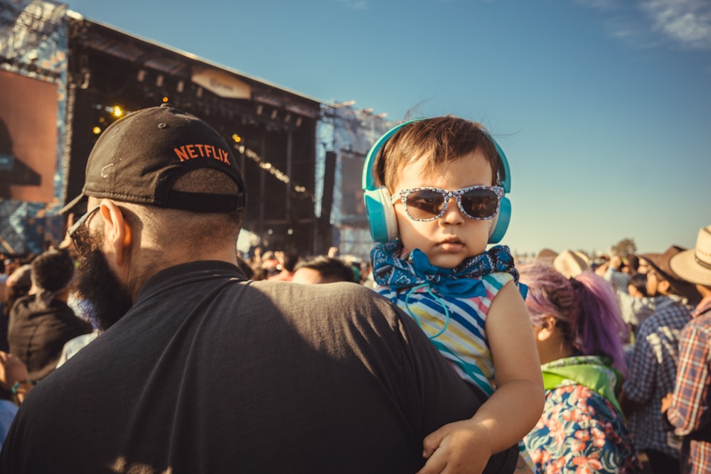 boy carrying a girl wearing sunglasses and headphones