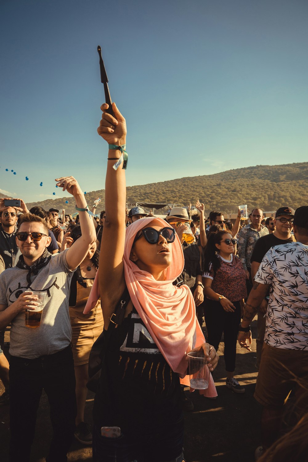 woman with pink shawl raising her right hand in front of people