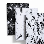 A collection of stylish, minimalist notebooks with unique graphic covers arranged on a wooden table