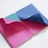 Two colorful notebooks with open pages showing vibrant pink, blue, and teal colors. The pages are curling slightly, revealing geometric patterns and designs printed on the inside.
